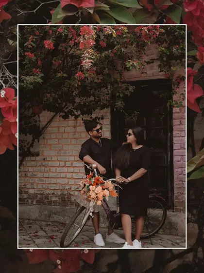 A romantic portrait of the couple with a bicycle adorned with flowers, framed by red bougainvillea.