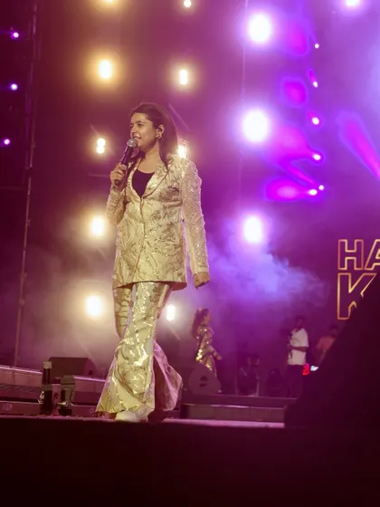 A dynamic shot of Hargun Kaur walking across the stage, surrounded by purple light and smoke. I capture the movement and energy of the performers.