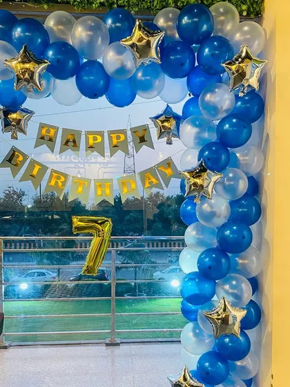 A simple and elegant balloon arch in blue and white for a 7th birthday party, decorated with star-shaped foil balloons.