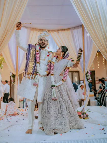 A joyful and celebratory pose from the bride and groom on their wedding stage.