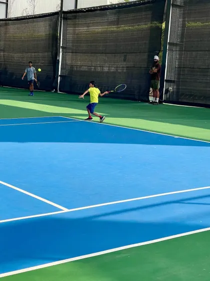 A junior player hits a powerful backhand during a competitive match. We develop well-rounded players with strong skills on both wings.