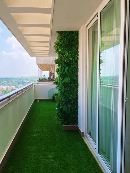 A narrow balcony in Dwarka is given a new life with a lush artificial grass floor and a vertical garden, creating a green view from inside the home.