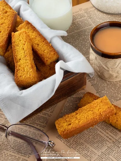 A lifestyle shot of rusks with tea, styled with a newspaper and glasses to create a "morning routine" feel. This helps customers connect with the product on a personal level.