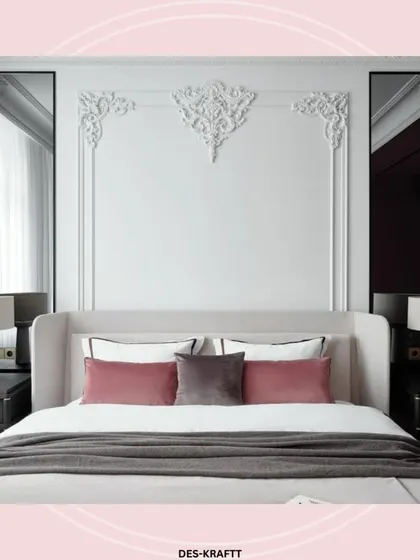 A bedroom that exudes classic elegance, with ornate wall moldings framing the headboard and soft mauve pillows adding a touch of romantic color.