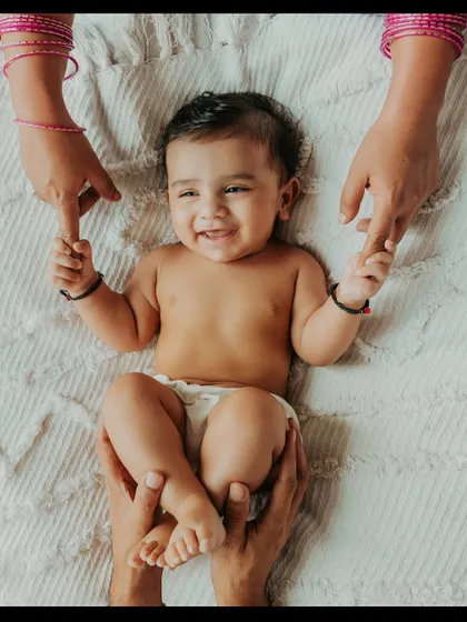 There is nothing more beautiful than a baby's smile. This moment, with mom and dad's hands holding their little one, captures the pure joy and connection that fills a new family. These are the simple, heartfelt memories I aim to preserve for you.