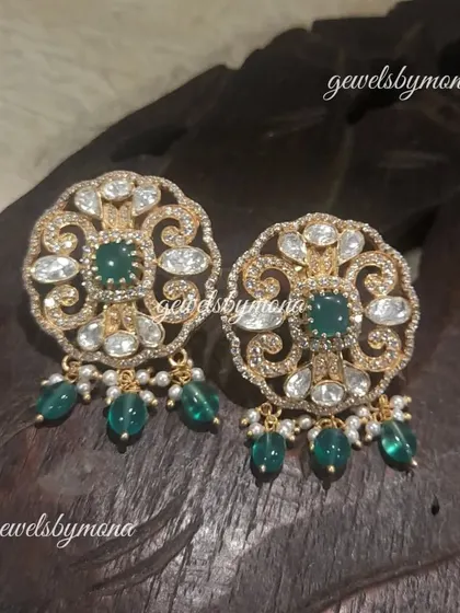 These round polki studs are adorned with delicate green bead drops. The intricate design and subtle color make them a versatile accessory for both traditional and contemporary outfits.