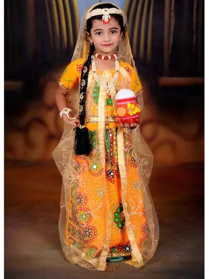 A full-length portrait of a young girl dressed as Radha for a Janmashtami shoot. The costume, jewelry, and props are all provided by the studio.