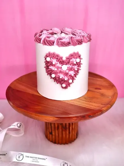 A simple yet beautiful tall cake with a heart made of intricate pink and white piping. This design is perfect for someone who appreciates detailed buttercream art and classic romantic themes.