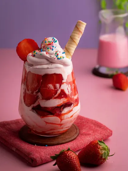 A close-up of our strawberry cream dessert, showcasing the vibrant colors and textures. The playful sprinkles and wafer roll add a touch of fun, making it perfect for a dessert parlor's menu.
