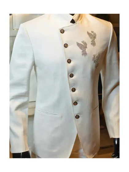 This unique white bandhgala features an asymmetric, overlapping front panel. The three hand-embellished birds add a touch of artistry, making it a modern and elegant choice.