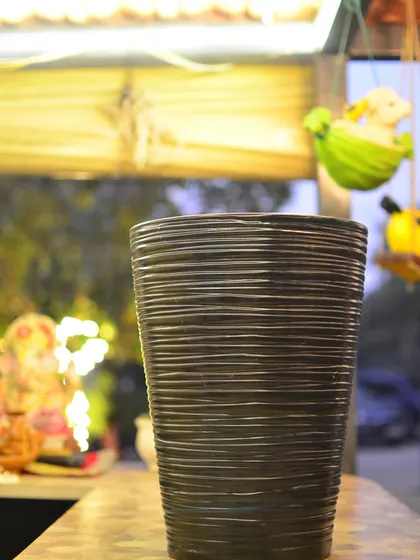 A close-up of a tall, dark planter with a horizontal ribbed texture, adding a sophisticated and modern touch to your decor.