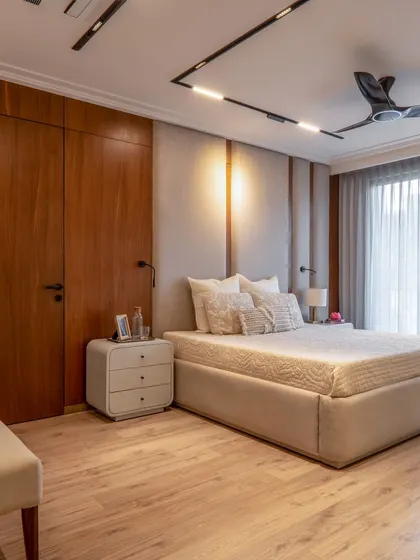 A beautiful blend of wood and fabric textures in this minimalist bedroom. The track lighting on the ceiling is a modern touch, while the wooden wardrobe and flooring add warmth and a natural feel.