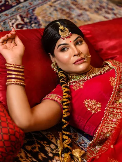 A graceful reclining pose that highlights the intricate braid and the rich details of the red lehenga. We create a complete storyboard to capture a variety of cinematic shots like this one.