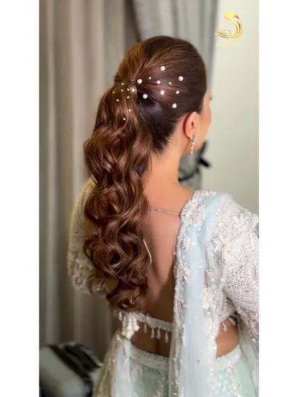A detailed shot of the pearl-studded textured ponytail. The pearls add a delicate and luxurious touch to the soft waves.