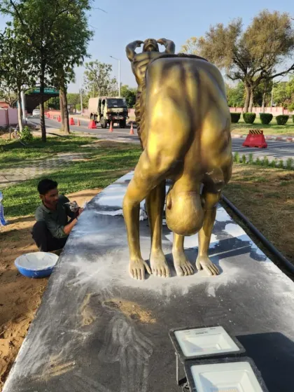 An artist adds finishing touches to the base of a Surya Namaskar statue. This view shows the 'Padahastasana' (Hand Under Foot Pose) from the series.
