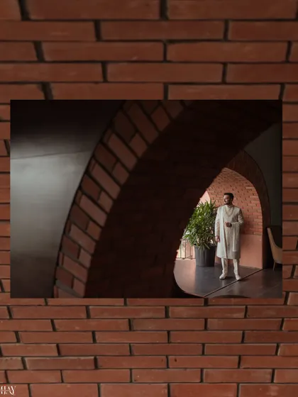 A creatively framed shot of the groom seen through a brick archway. This composition uses architectural elements to create a sense of depth and focus, resulting in a unique and artistic groom portrait.