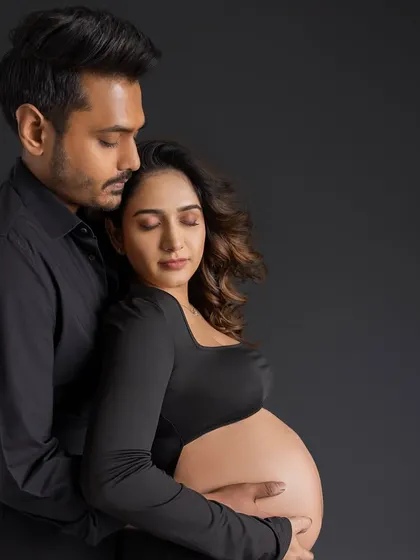 A serene and peaceful portrait. The couple stands together with their eyes closed, lost in the moment, conveying a sense of calm and deep connection as they await their baby.