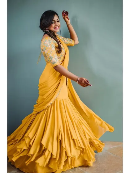Capturing movement and joy in a modern ethnic outfit. This shot showcases a unique ruffled lehenga-saree, with the model's twirl creating a dynamic and lively fashion portrait.