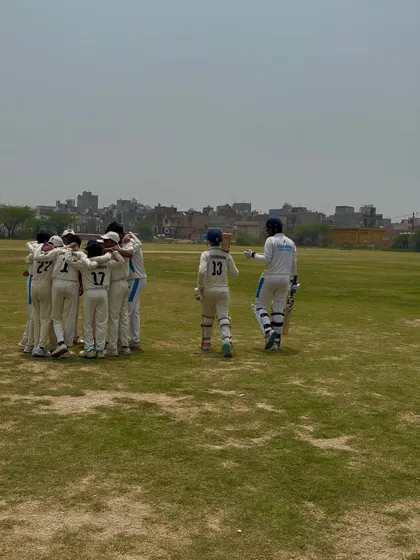 The team in a huddle, with the opening batsmen walking out. A picture of unity.