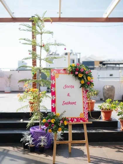 A simple and sweet welcome sign for the couple, adorned with a fresh floral arrangement, greeting guests to the celebration.