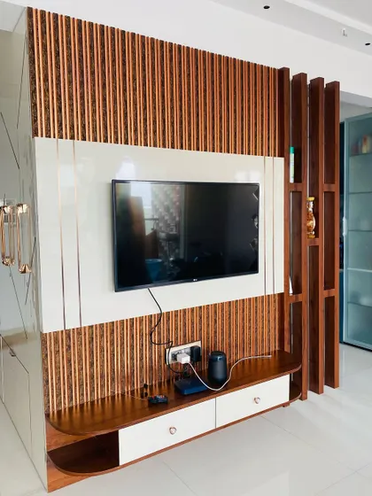 Here, I used vertical wooden louvers to create a modern TV background and a matching partition. This design adds warmth and texture while maintaining an open and airy feel in the living area.