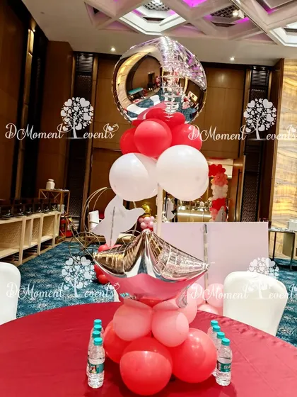 A festive star and orb balloon centerpiece on a red tablecloth, perfect for a Christmas-themed celebration.