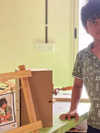 This young carpenter stands beside the photo frame he built, a great first project in woodworking.