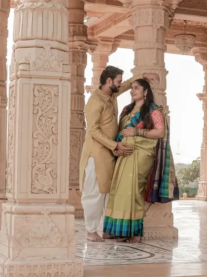 A regal portrait of the couple amidst intricately carved pillars. Their traditional attire complements the grandeur of the outdoor architectural location.