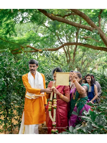 A candid shot of a wedding ritual taking place outdoors, surrounded by the beauty of nature.