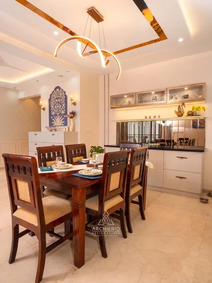 This dining room combines traditional wooden furniture with modern design elements like a mirrored crockery unit and a stylish chandelier. The blue wall art adds a unique, personal touch.