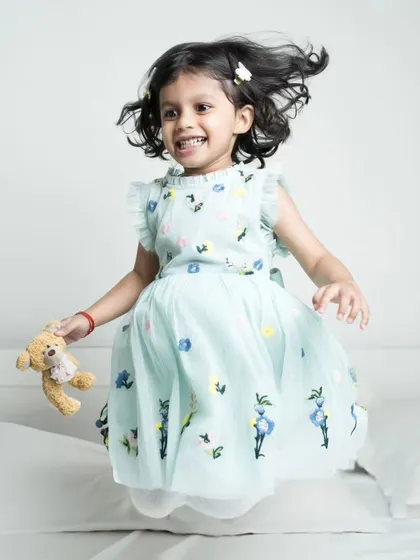 Pure energy! A little girl jumps on the bed, her hair flying and a huge smile on her face. A perfect example of a fun, candid moment.
