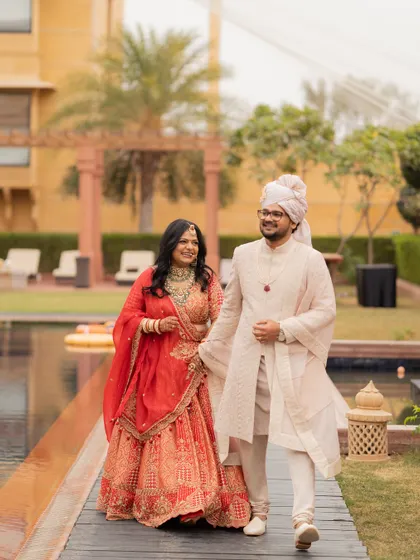 The couple taking a stroll by the palace pool, showcasing their complete, coordinated royal wedding looks.