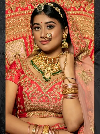 This bride is ready for her big day in a classic red and gold lehenga. The makeup features a sharp winged liner and a perfectly matching red lip, a timeless combination for any Indian bride.