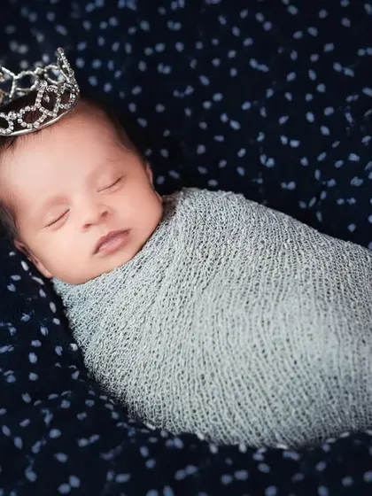 A tiny prince! This sleeping newborn wears a small crown, adding a touch of royalty to his first portrait.