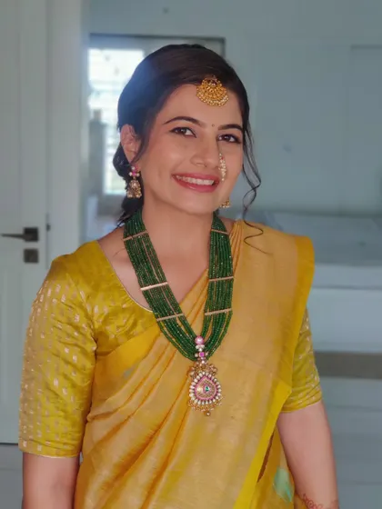 The yellow saree paired with a green beaded necklace creates a beautiful contrast.