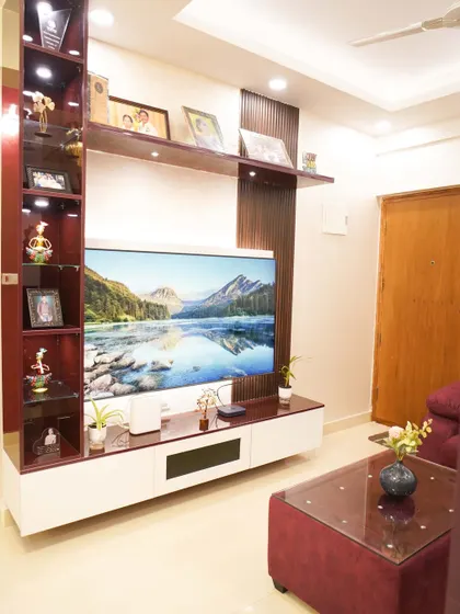 A grand TV and display unit in a rich mahogany finish with integrated shelving and backlighting. This custom piece serves as the focal point of the living room, combining storage and style.