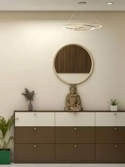 A clean and contemporary foyer with a long, low shoe cabinet in a two-tone finish. The round mirror and Buddha statue add a touch of zen-like calm.