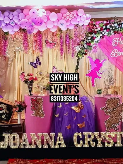 An "Angel theme" for Joanna Crystal's first birthday, filled with shades of purple and pink. The decor includes fairy and angel silhouettes, butterfly accents, and a floral arch.