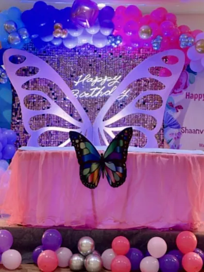 A twins' birthday party with a beautiful butterfly theme. The setup includes marquee numbers '1' and '3' and a large butterfly prop against a sequin wall.