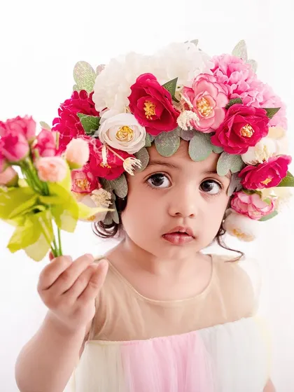 A unique and artistic portrait, this little girl wears a magnificent crown of flowers, looking like a true queen of the garden.