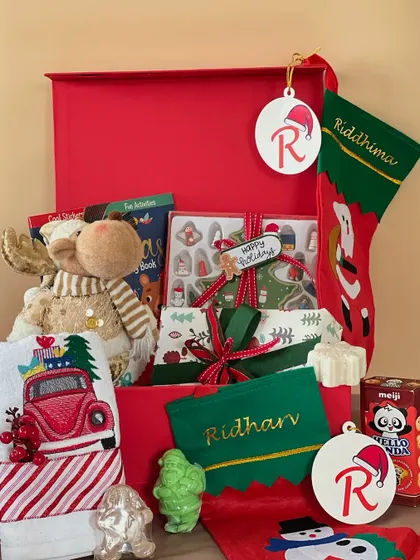 Here's what's inside the kids' Christmas hamper! It's packed with a reindeer soft toy, personalized stockings and ornaments, a custom-embroidered towel, and some yummy treats.