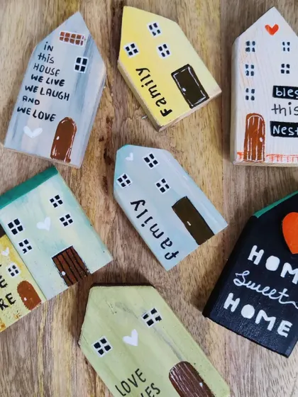 A collection of our standalone miniature wooden houses. Each one is hand-painted with sweet quotes and details, perfect as small shelf decor or fridge magnets.