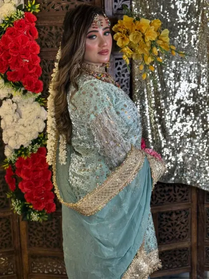This bride-to-be looks stunning in her pastel green outfit for a pre-wedding event. Her makeup is soft and glowing, with long, wavy hair and a beautiful floral hair accessory.