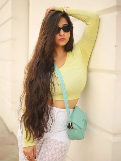 A classic fashion pose against a clean, white pillar, emphasizing the model's silhouette and the texture of her outfit.