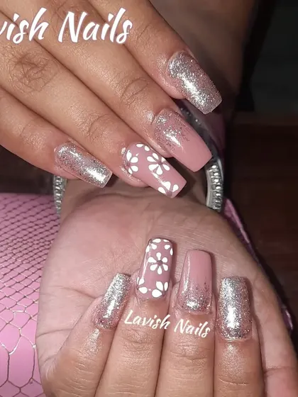 A chic combination of dusty rose and full-coverage silver glitter nails, with a delicate white floral pattern on the accent nails.