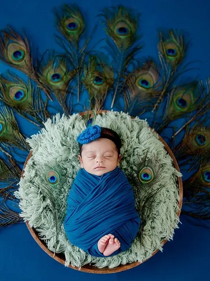 A stunning and vibrant setup using a fan of peacock feathers as a backdrop. The deep blue wrap and basket complement the theme beautifully.