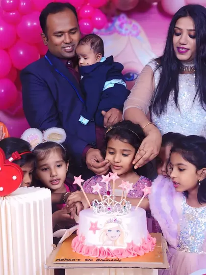 Capturing the joy of a Barbie-themed birthday party. The family gathers for the cake-cutting in front of the beautiful pink decor.