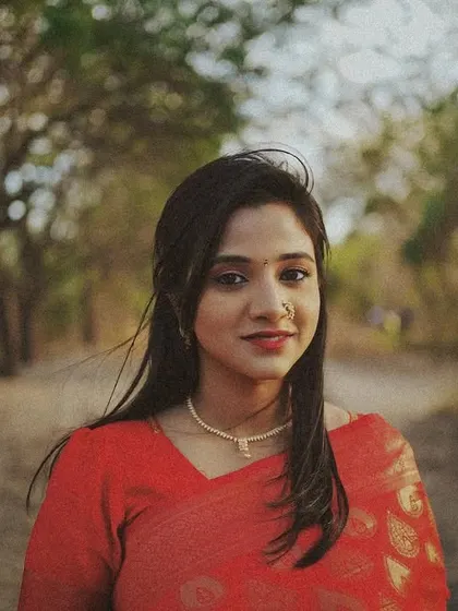 A vintage-style 35mm portrait of a woman in a red saree, with a soft focus and warm tones creating a nostalgic feel.