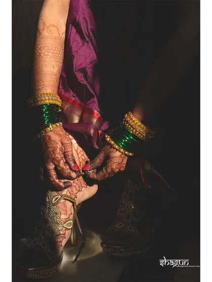 A detail shot of the bride's feet, adorned with mehndi and payal, as she puts on her traditional juttis.