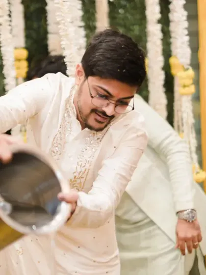 The groom's friends get ready to pour a bucket of water on him, a classic Haldi prank. The anticipation and laughter make this a great documentary shot.